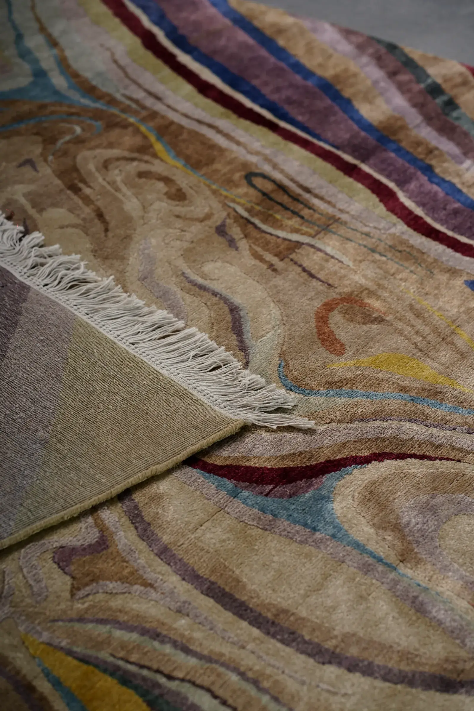 A rug folded back to show the fringe and the knots