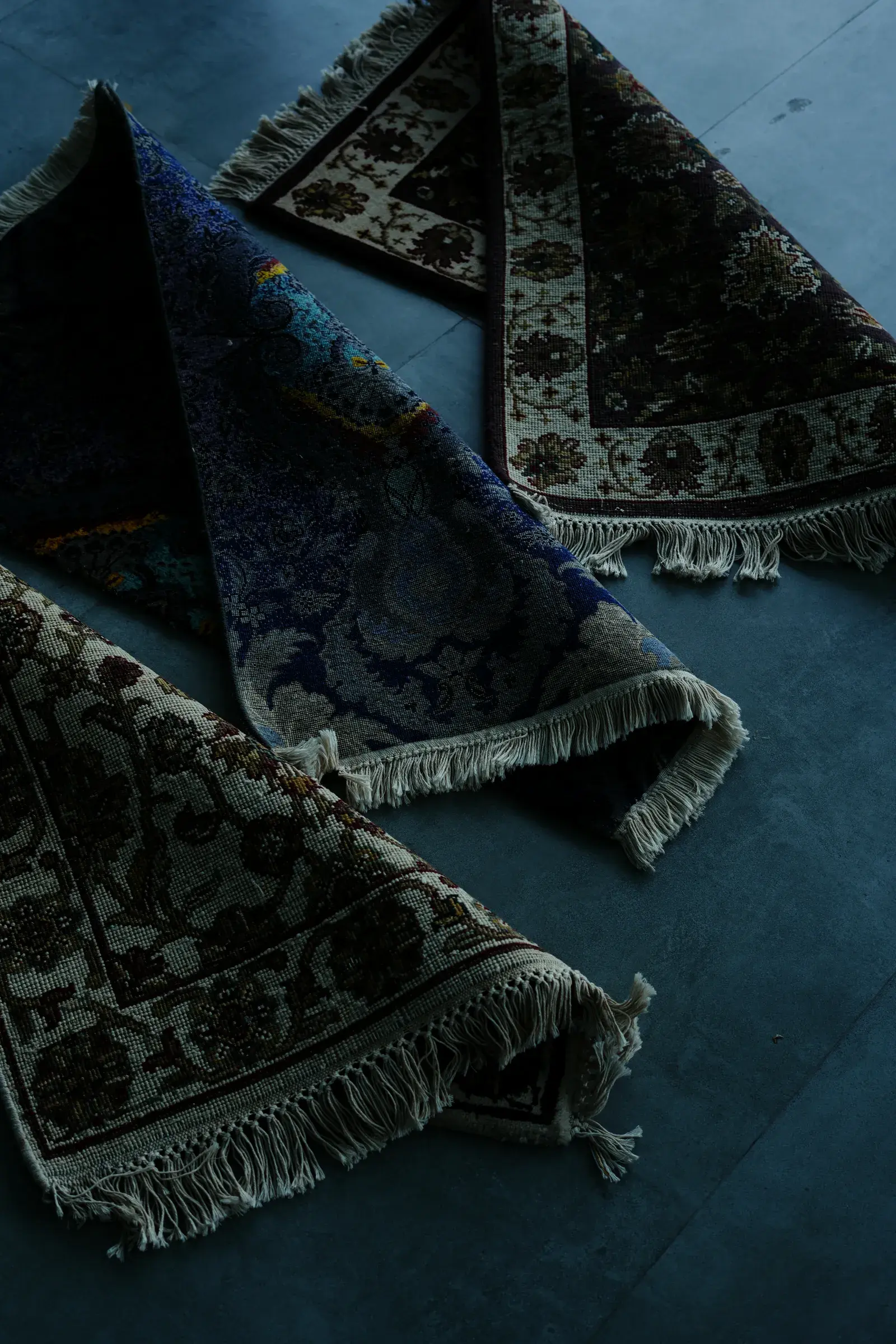 Three rugs stacked with their corners folded back