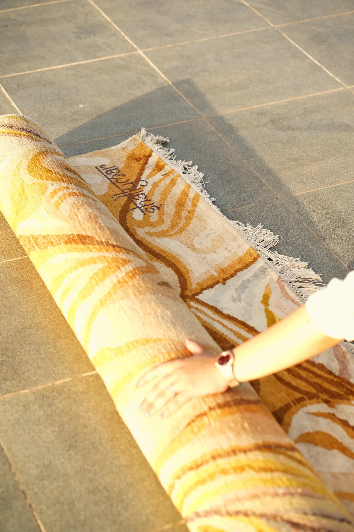 Rati, a honey and ivory Shallymar rug being rolled out by hand