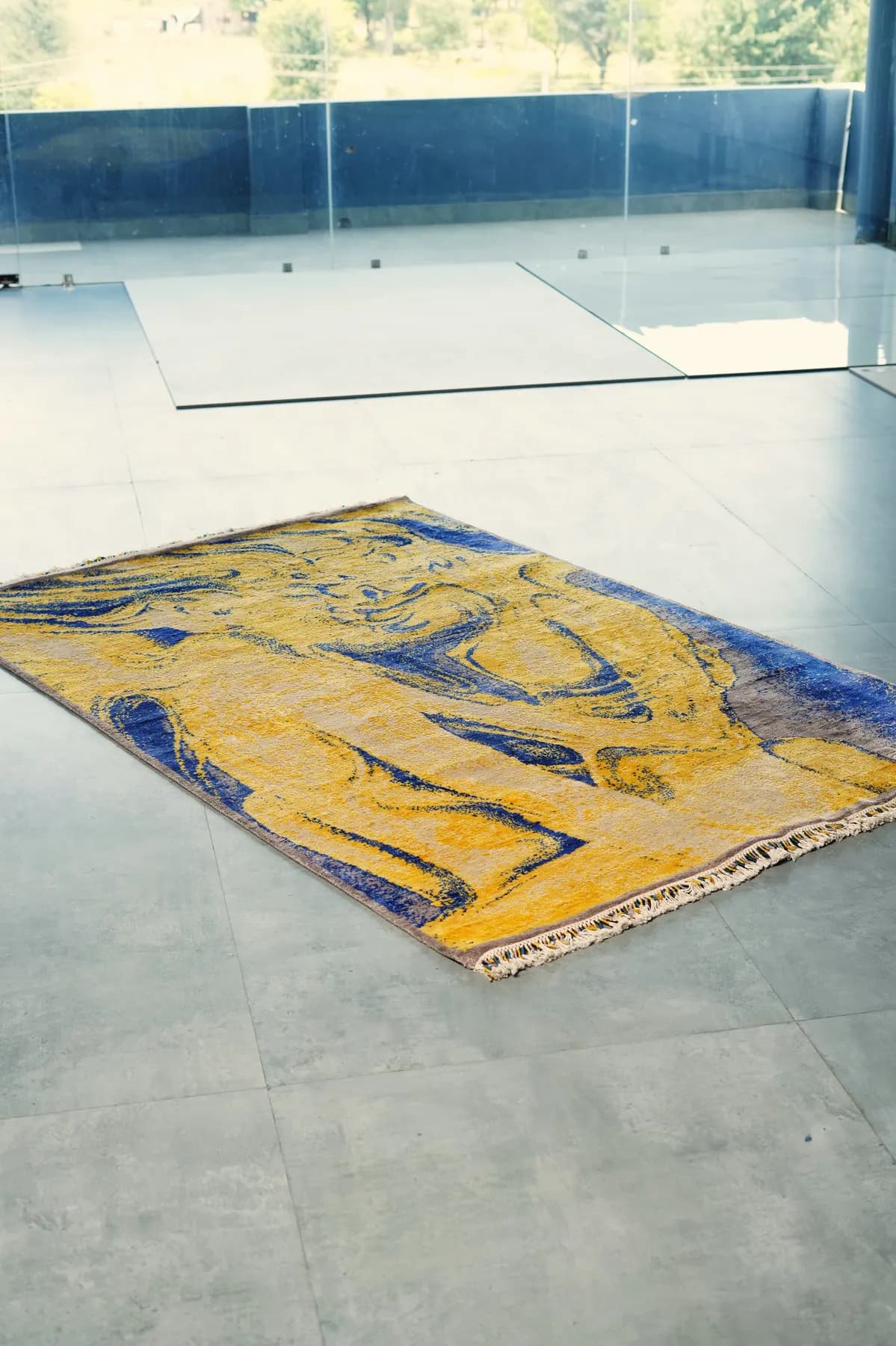 Malya, un tapis Shallymar jaune et cobalt drapé dans une pièce sombre
