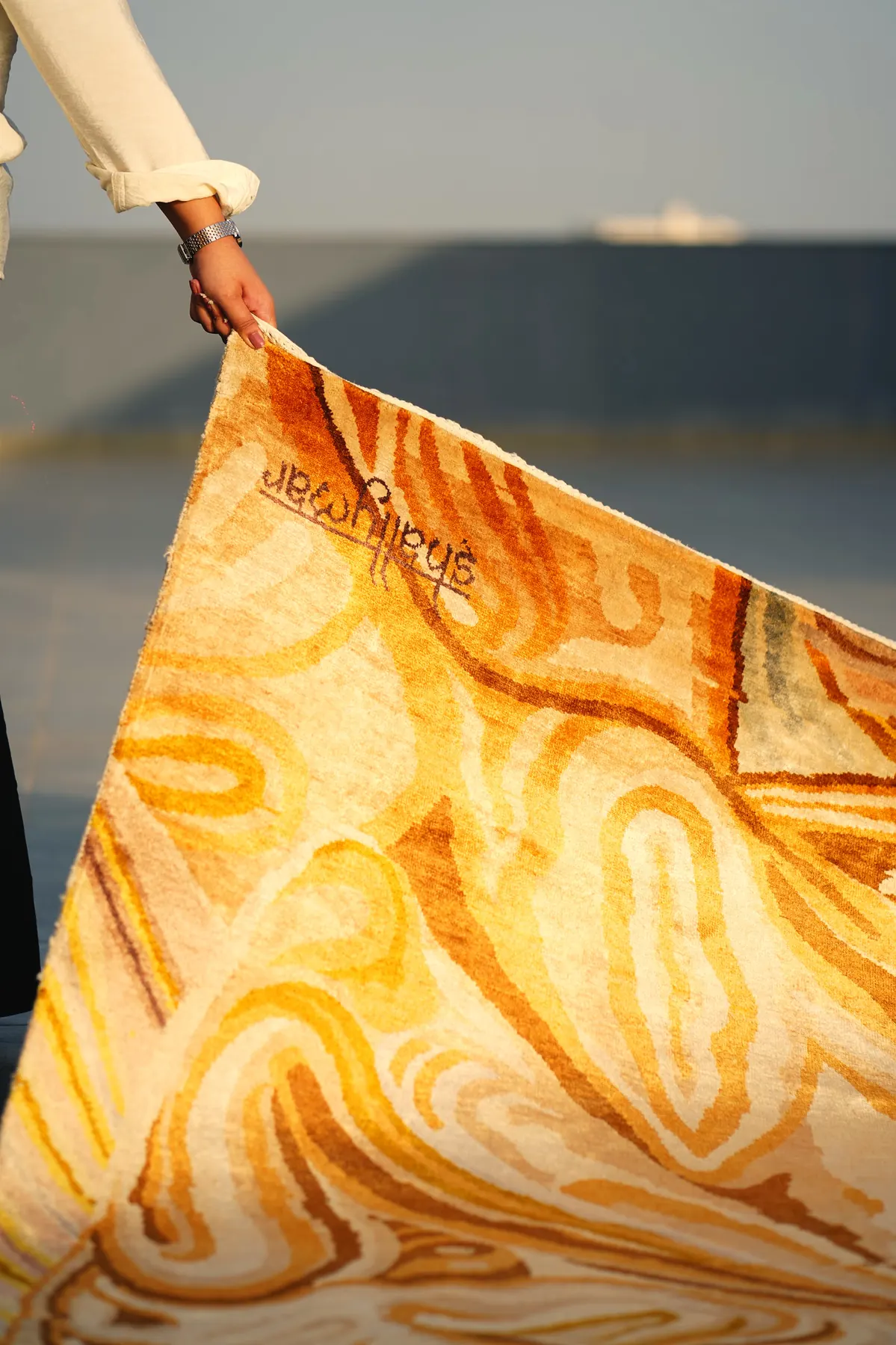 Rati, a honey and ivory Shallymar rug being rolled out by hand